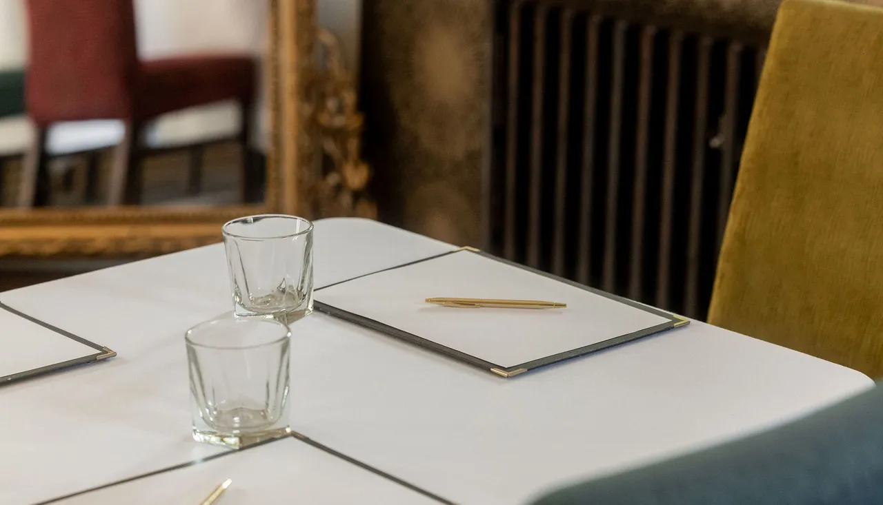 Elegant table set with notepads, pens, and glasses in a stylish, sunlit room