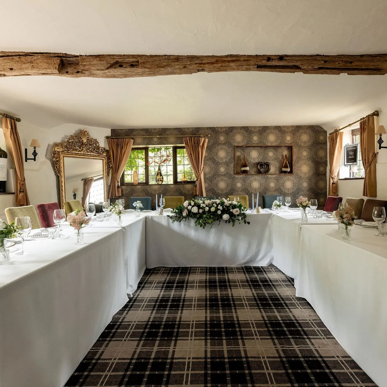 Elegant dining room with U-shaped table setting, floral centerpiece, and rustic decor