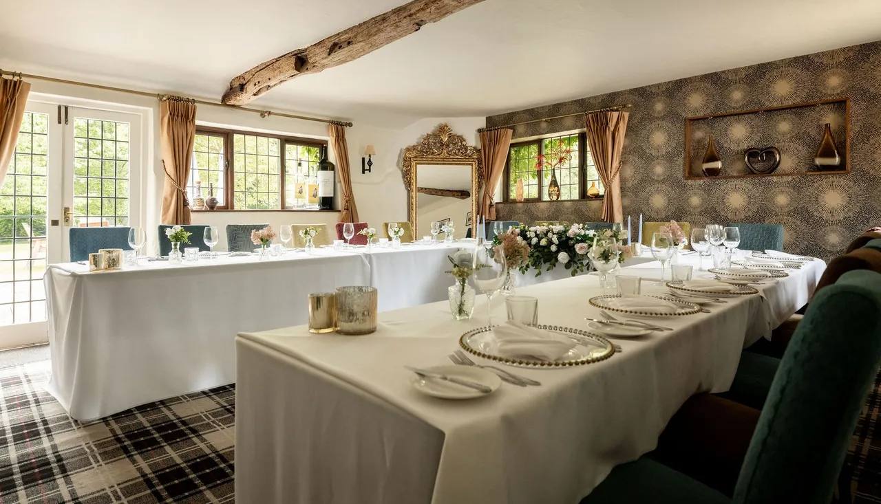 Elegant dining room setup with white tablecloths, floral centerpieces, and decorative elements in a cozy, light-filled space.