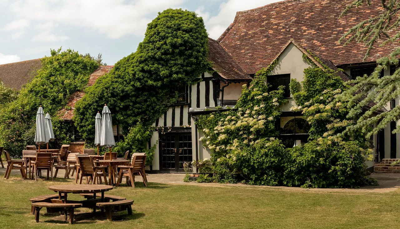 Traditional English countryside building with outdoor seating and lush greenery