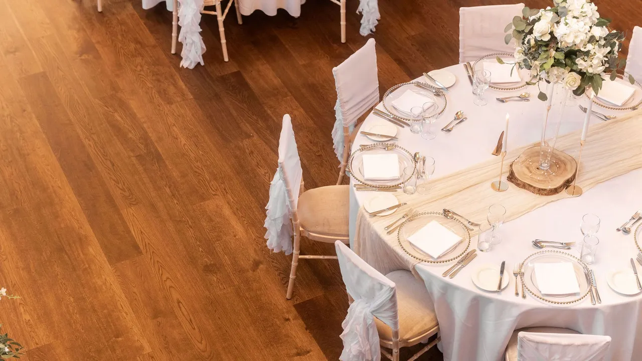 Elegant round table set for a formal event with white tablecloth, decorative centerpiece, and neatly arranged plates and cutlery.
